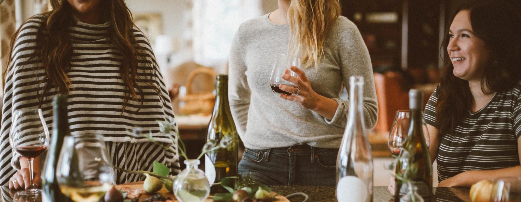 a group of women stand around a table with food