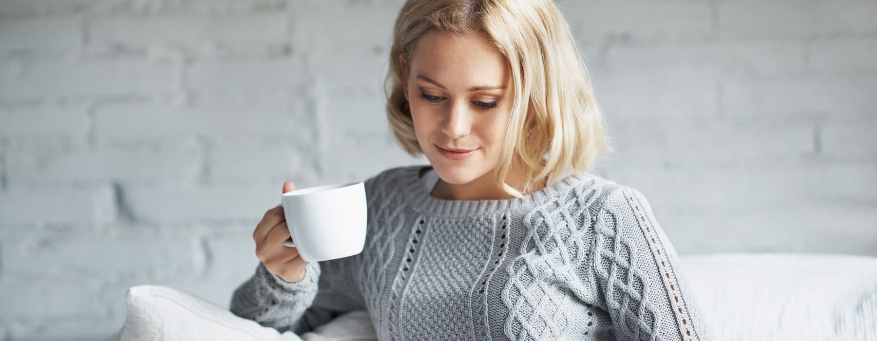 a person sitting down holding a cup looking at a tablet